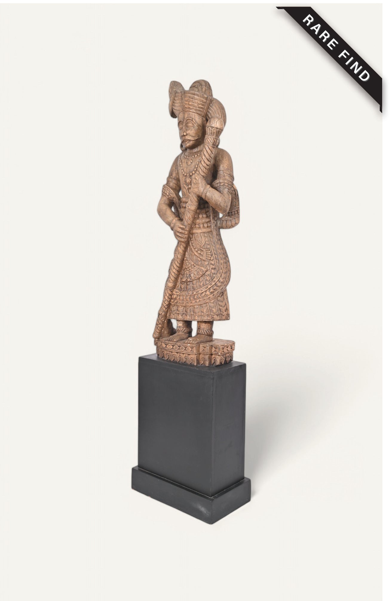 A handcrafted wooden statue of a traditional guard, seated on a black pedestal