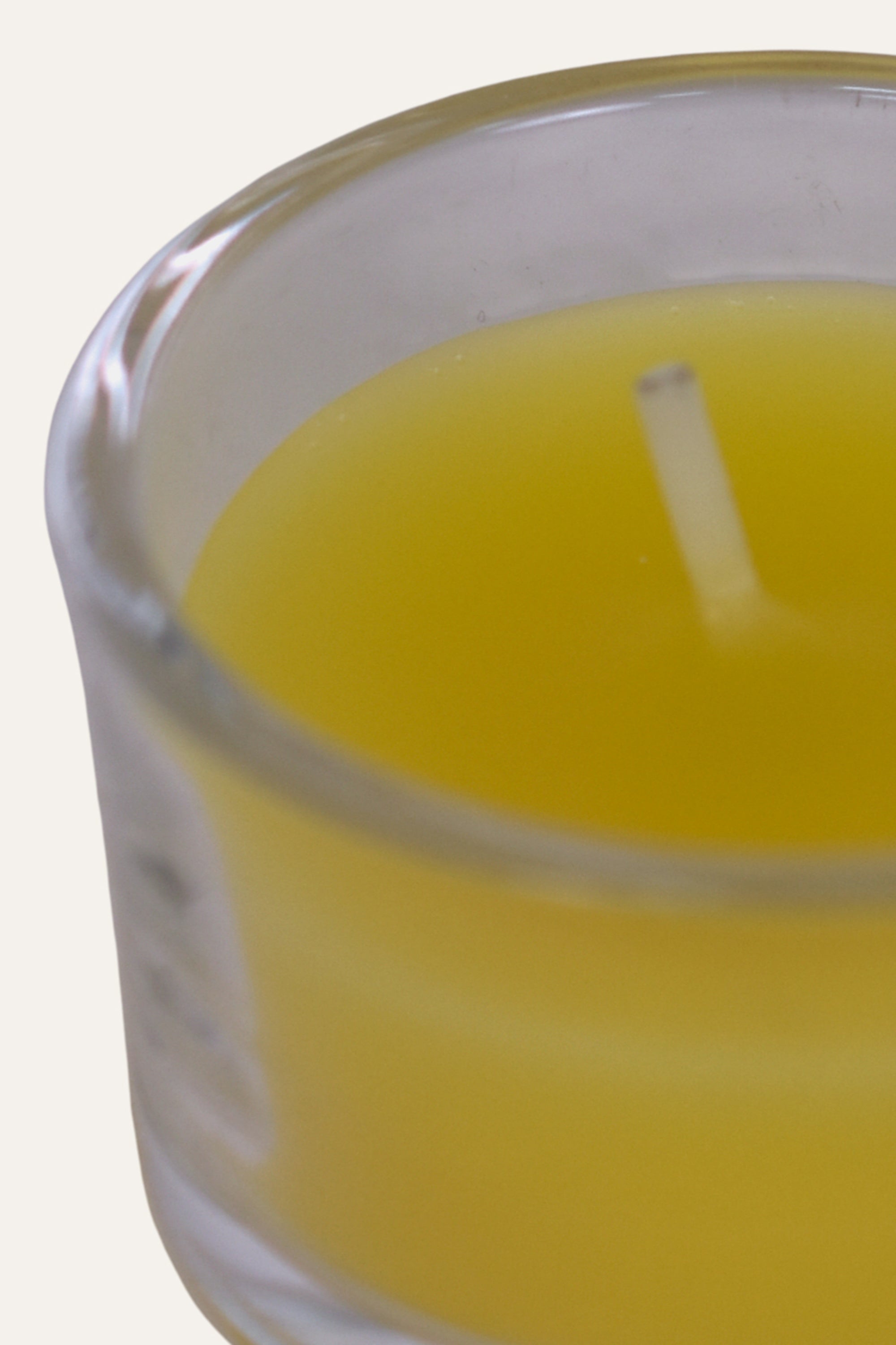 Yellow candle in a clear glass holder