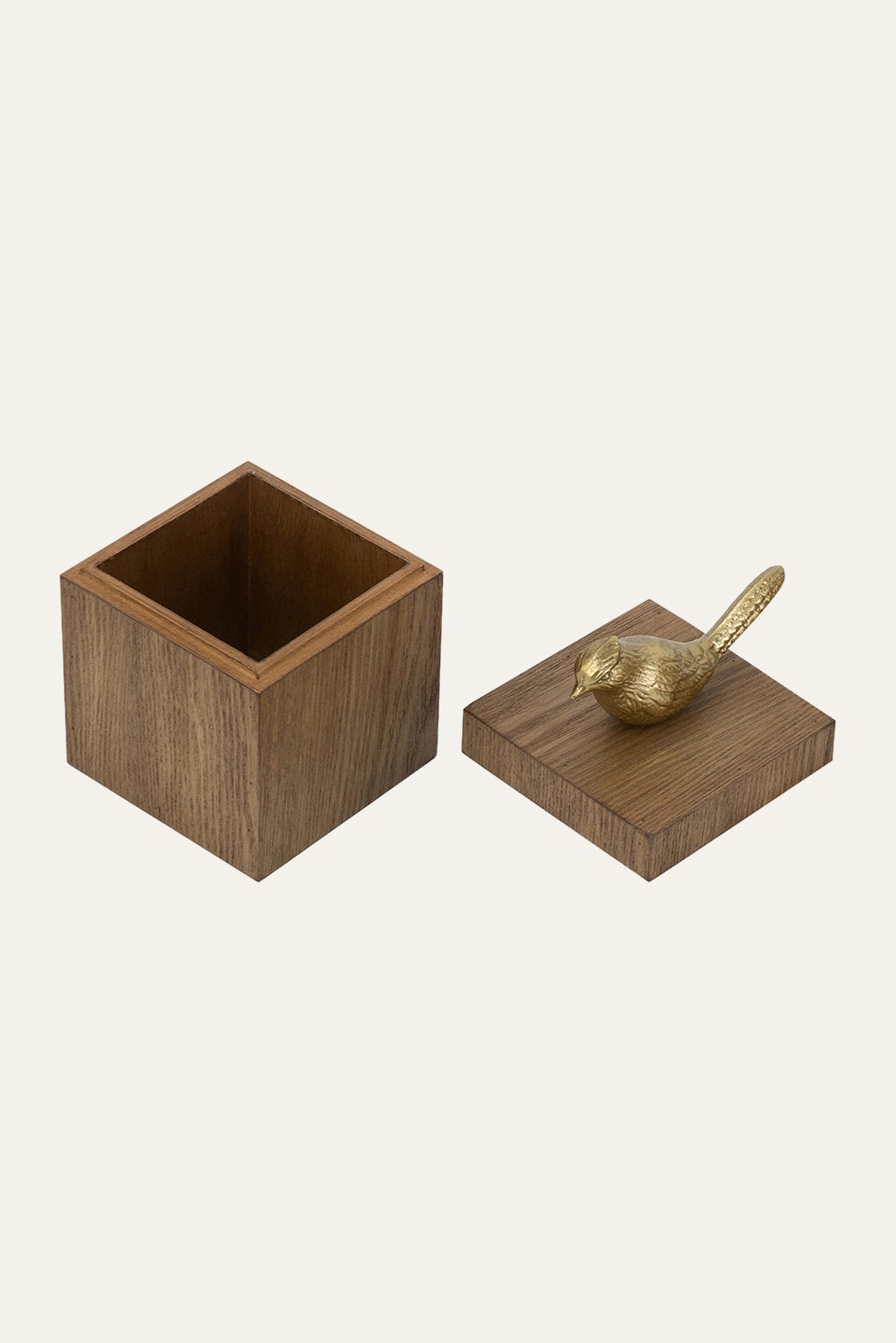 Wooden cube with a gold bird figurine