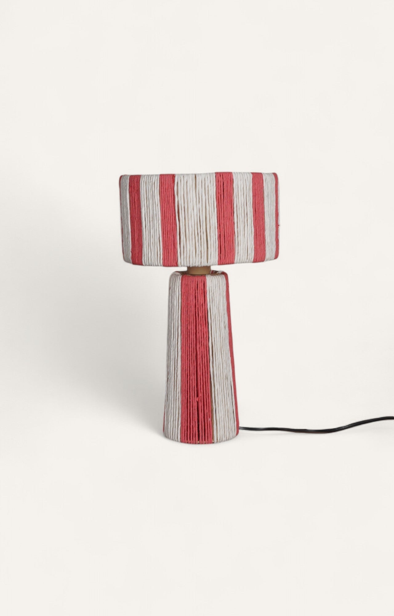 Table lamp with vertical orange and off-white stripes created from textured raffia ropes around a metal frame.